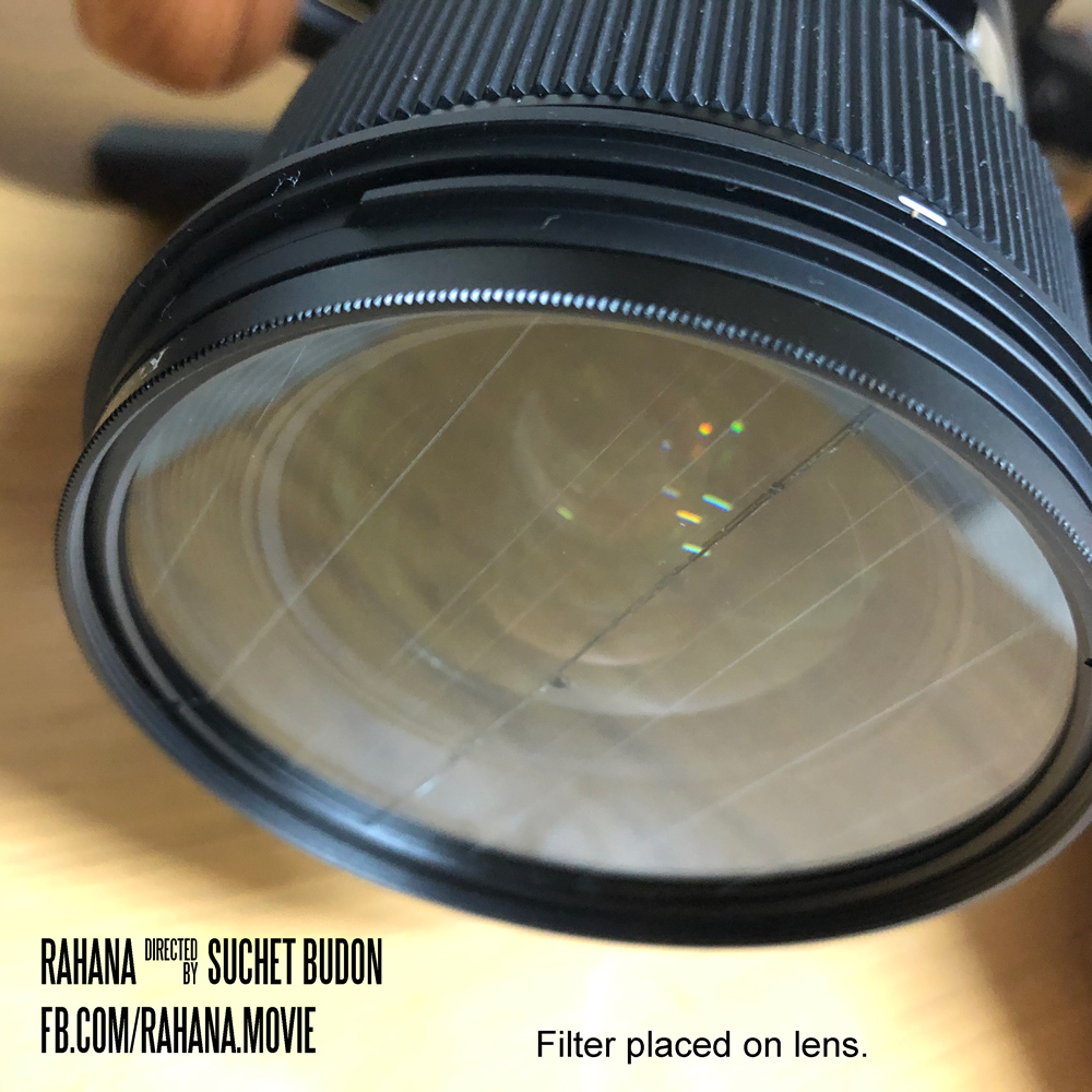 A filter with lines cut into it being placed on a 24mm lens (77mm width) attached to a Sigma fp camera